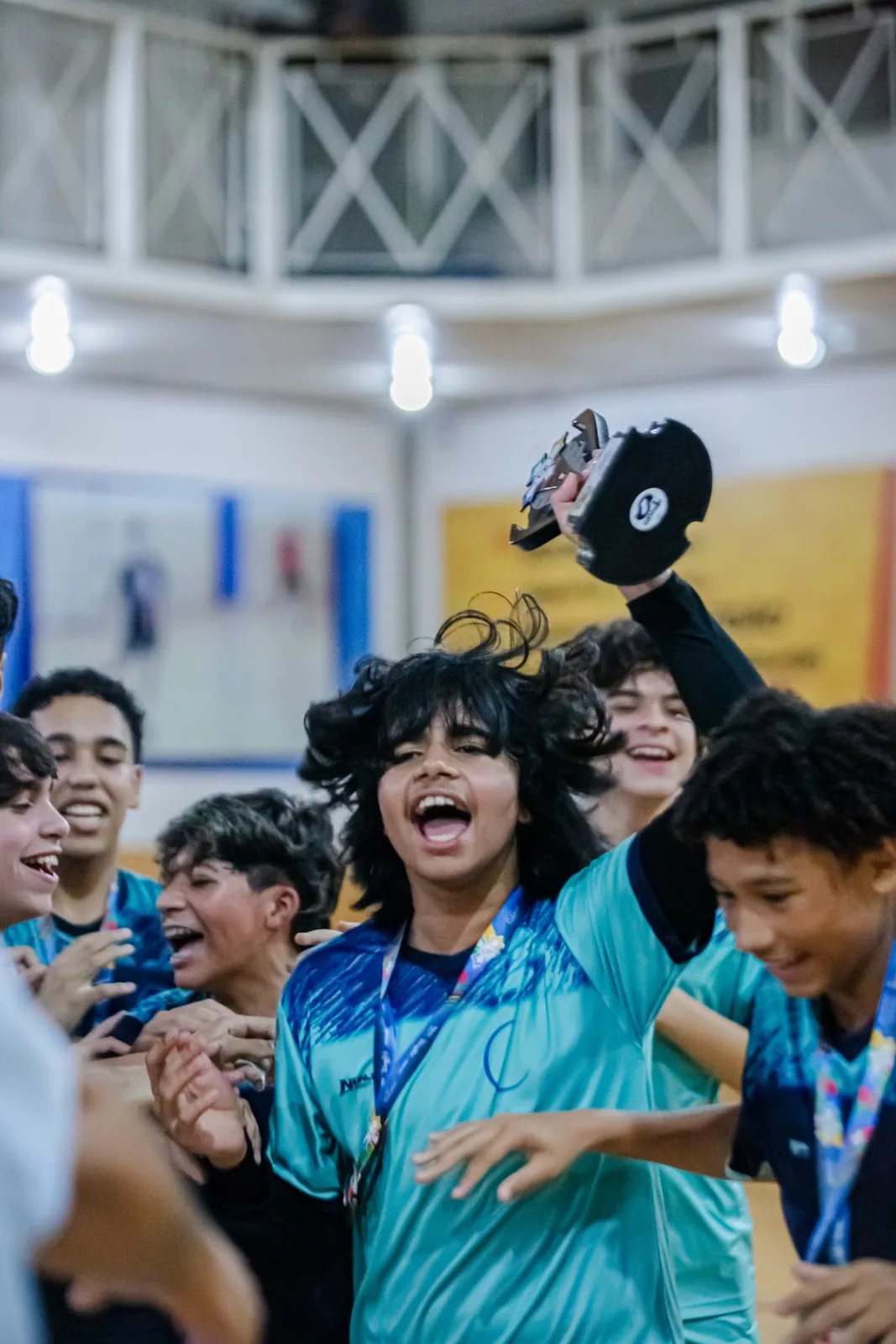 Equipe comemorando com o troféu e medalhas após competição escolar