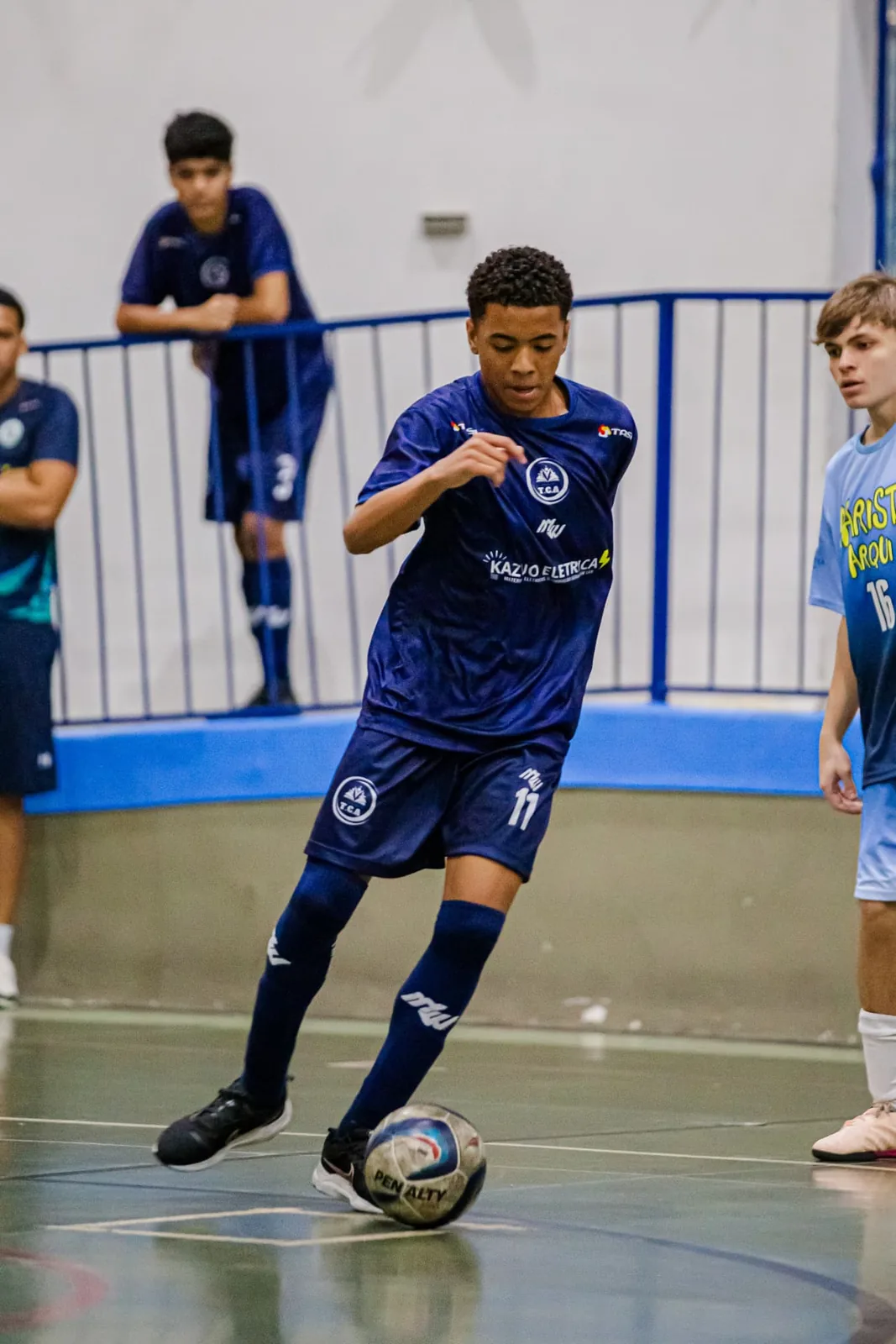 Atleta conduzindo a bola com foco durante partida de futsal