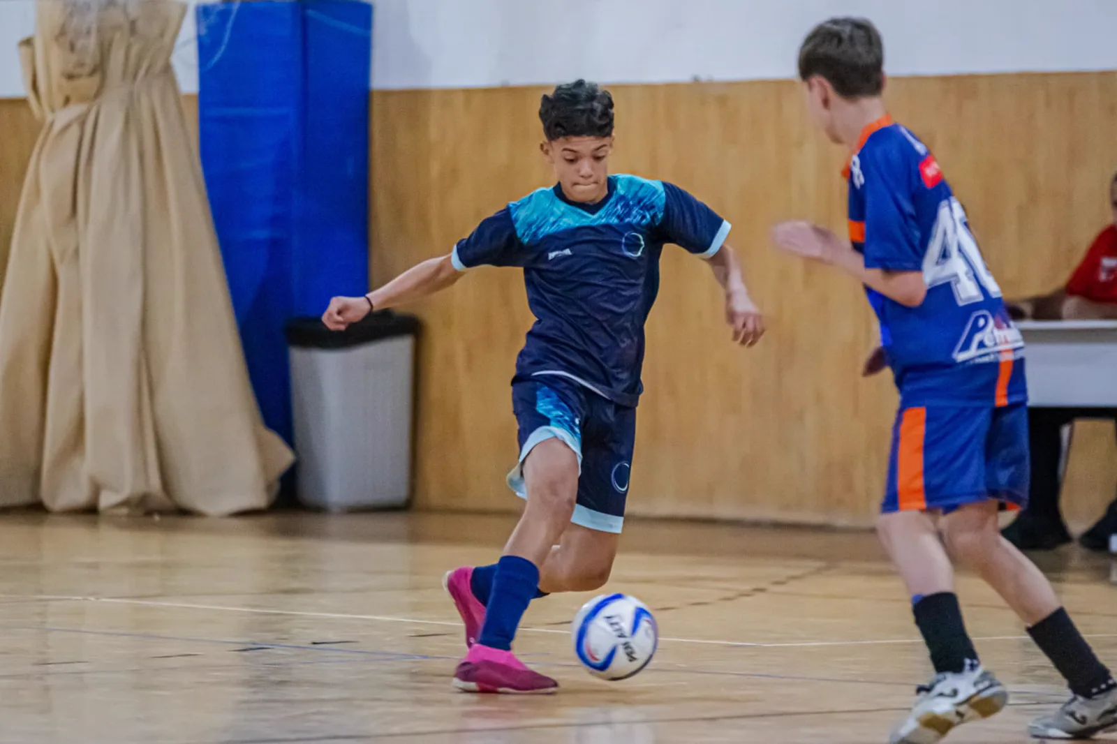 Atleta conduzindo a bola em jogo de futsal